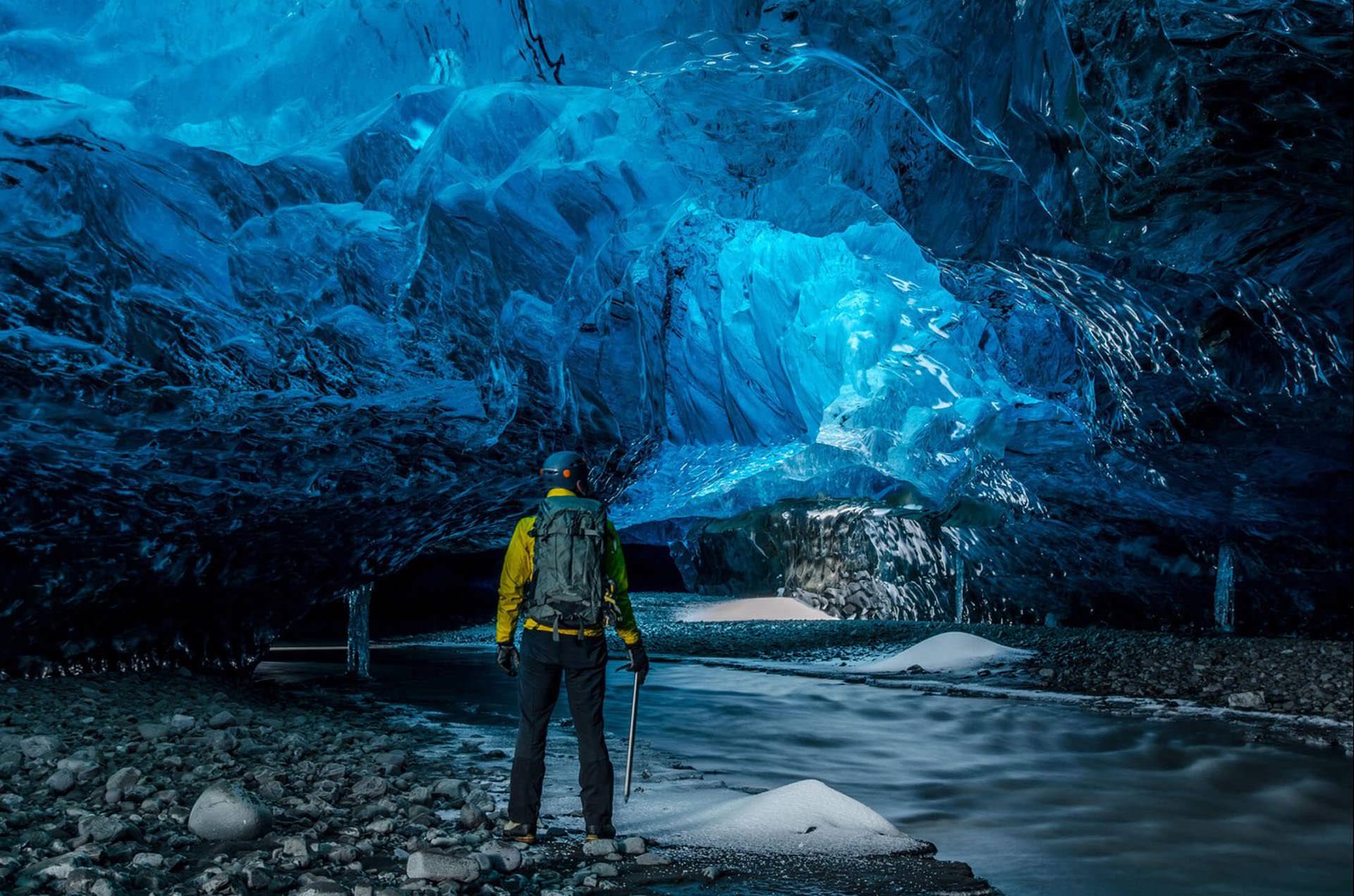 Traveler standing inside a sapphire blue ice cave in an Icelandic glacier
