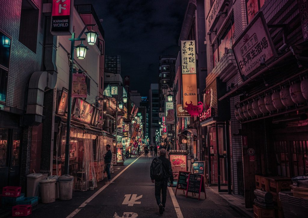man walking down lit alleyway japan tokyo nightlife