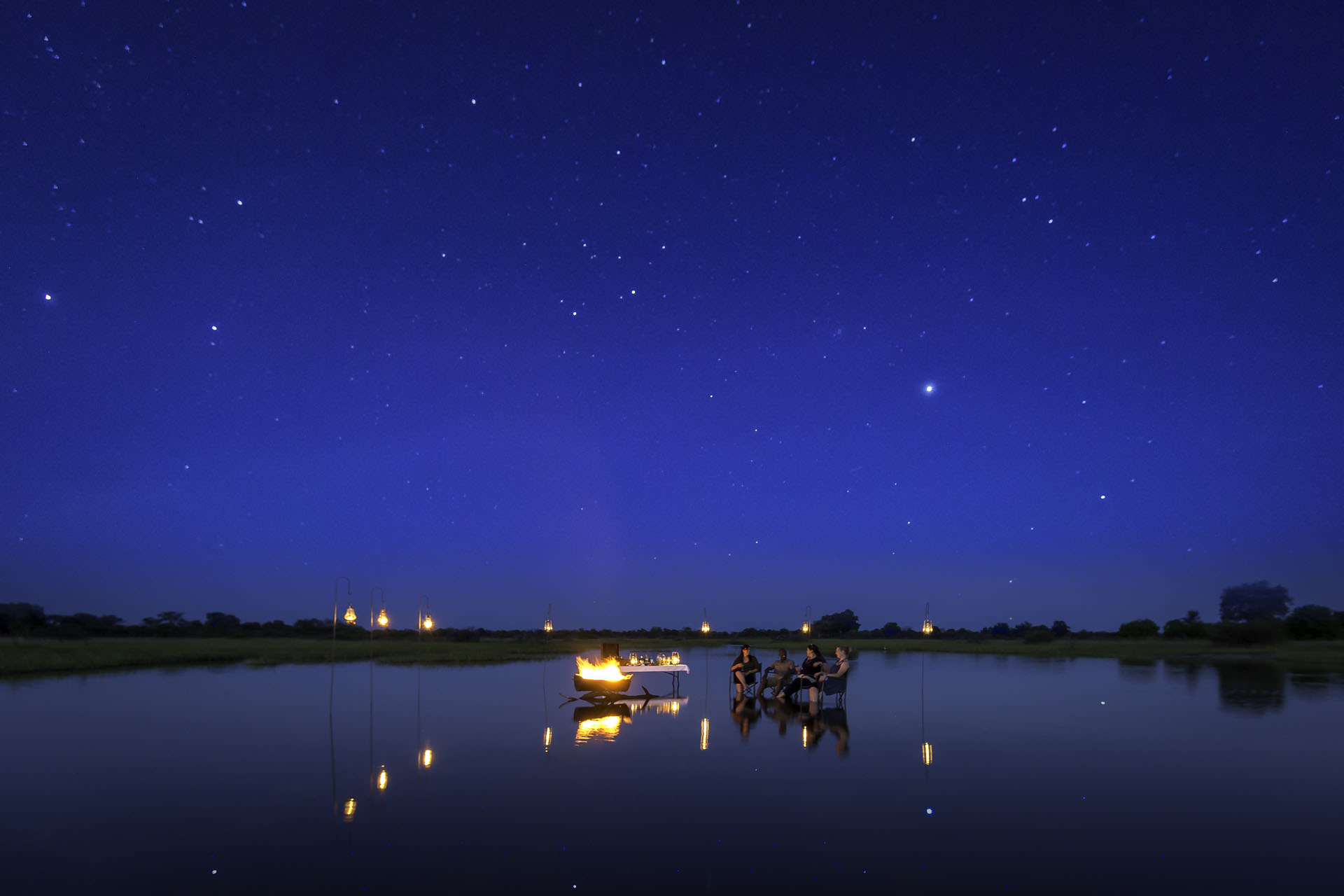 Night safari in Botswana featuring safari guests under a star-filled sky