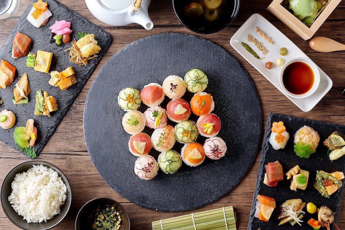 Artfully presented Japanese kaiseki cuisine with colorful bite-sized dishes arranged on dark stone plates