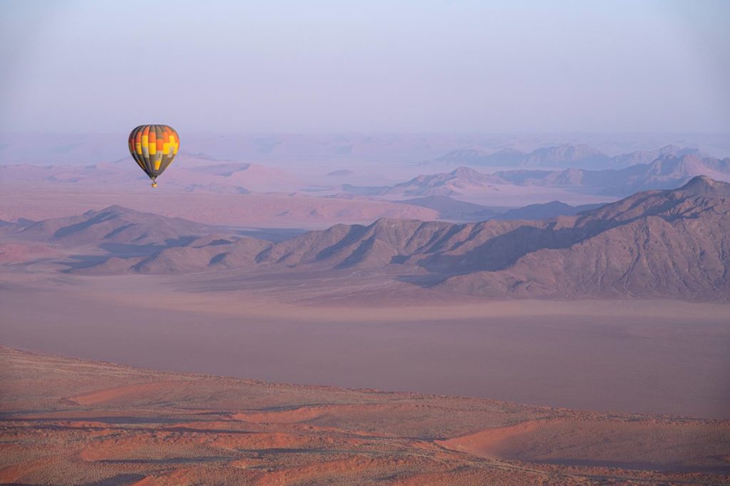 Luxury safari hot air balloon experience over Namibia’s dramatic desert landscapes at dawn