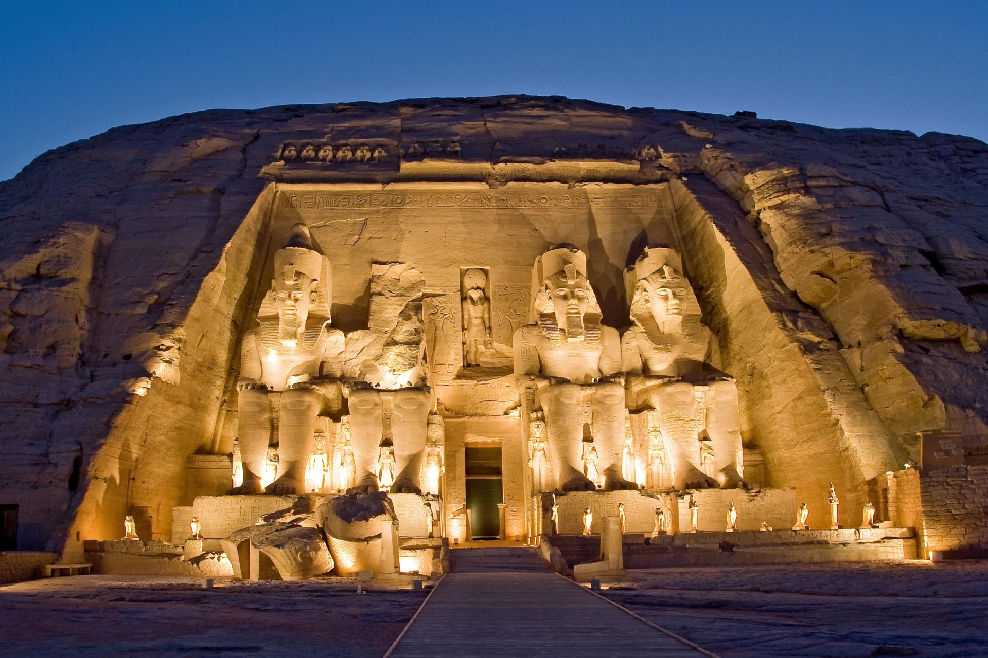 Illuminated Abu Simbel temple at night featuring colossal statues of Ramses II carved into sandstone