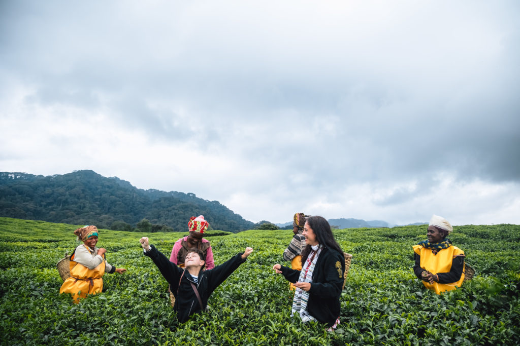 Travelers and local guides standing among lush green plantation fields in a scenic rural landscape
