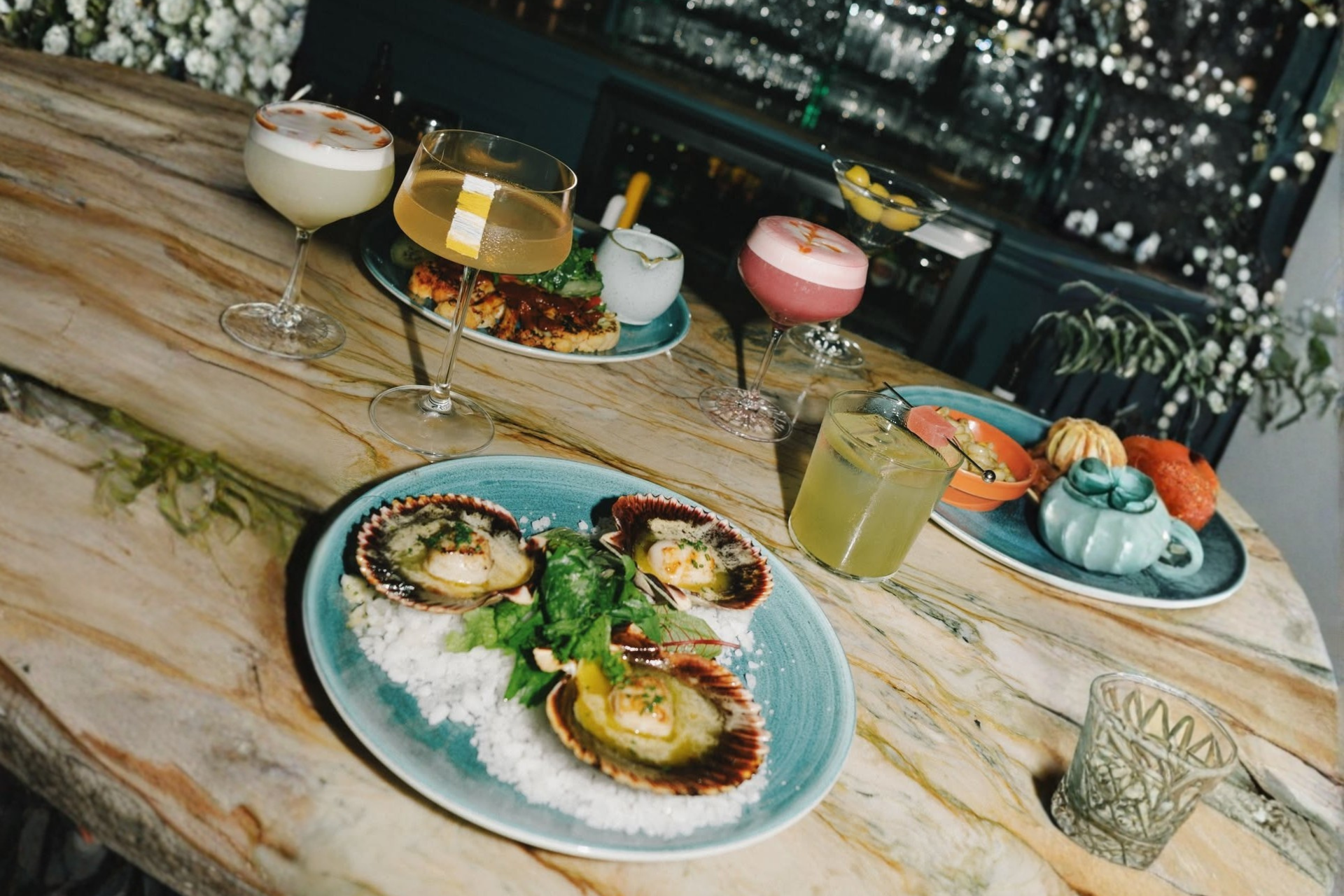 Gourmet dishes and crafted cocktails on a restaurant table, reflecting high-end dining experiences with sought-after reservations