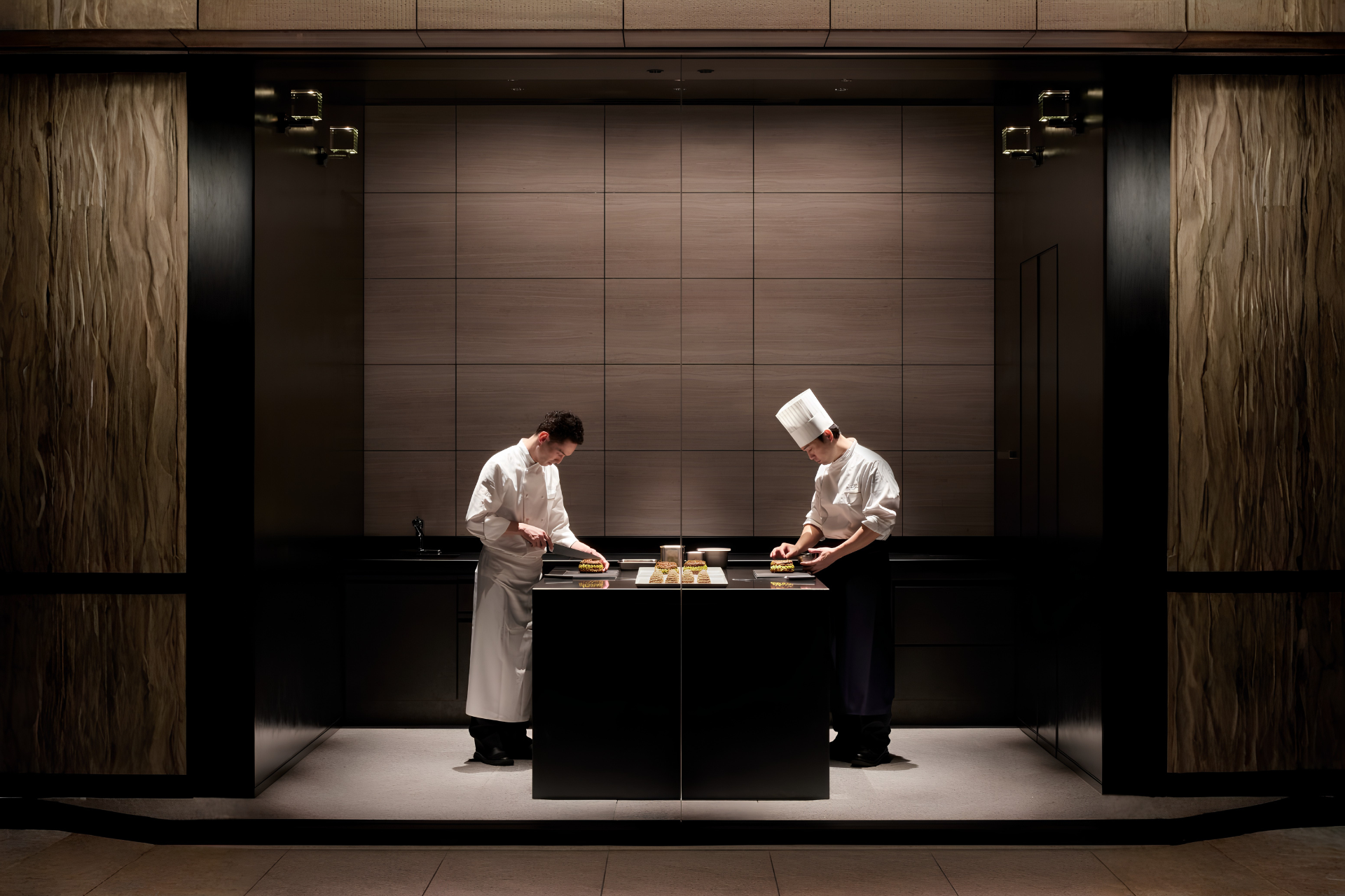 Chefs preparing dishes in a minimalist kitchen, representing learning from a master chef in an exclusive culinary travel experience