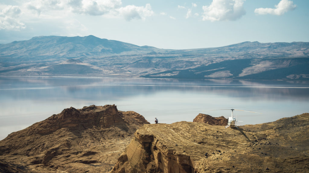 Helicopter landing on remote Kenyan cliff above a lake, representing high-value, specific content that improves SEO and AI visibility