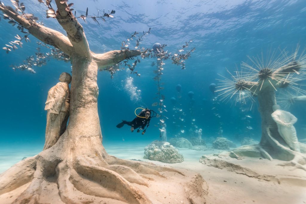 Diver exploring an underwater sculpture garden designed to support coral regeneration in Turks and Caicos.