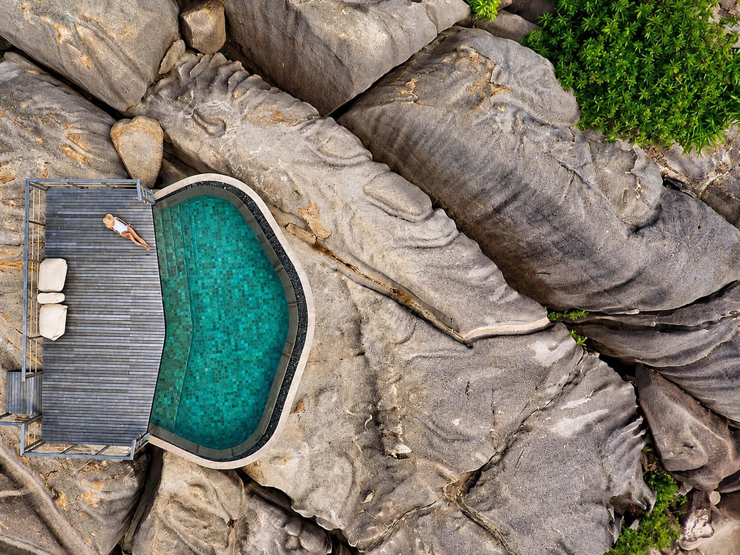 Aerial view of a plunge pool and deck set into granite boulders in the Seychelles